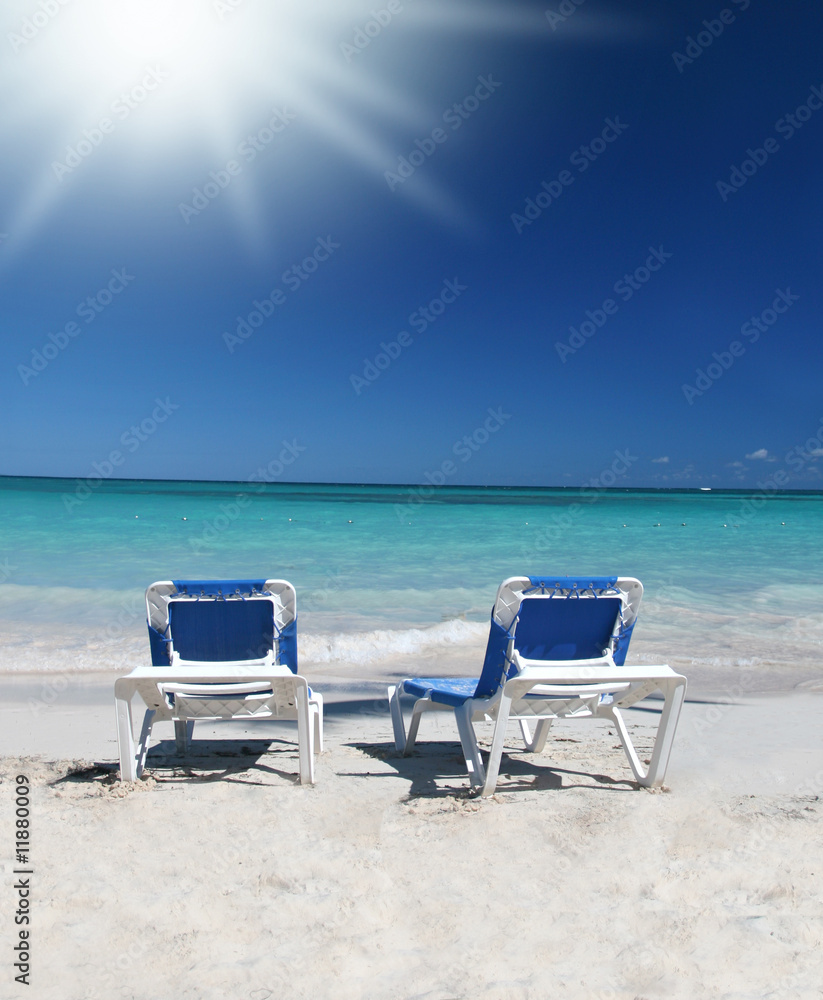 Two Lounge Chairs on White Sand Beach and Ocean Background Two Lounge Chairs on White Sand Beach and Ocean Background