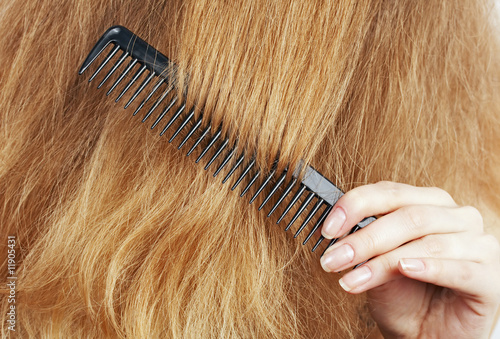 woman combing long blond wavy hair, beauty salon