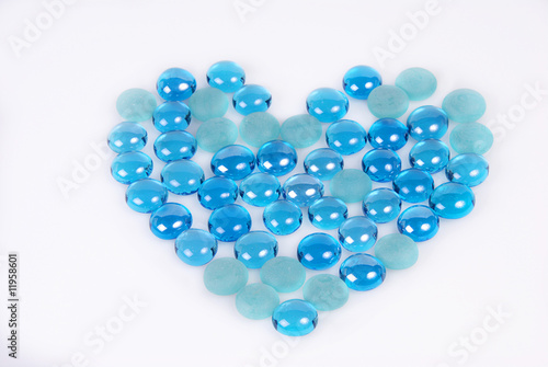 Blue glass stones shaped as a heart on white background with copy space.