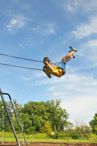 Young girl on swing against a blue sky