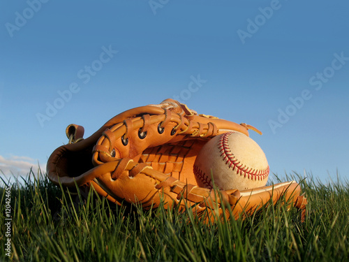 Baseball glove with ball resting in a grass field
