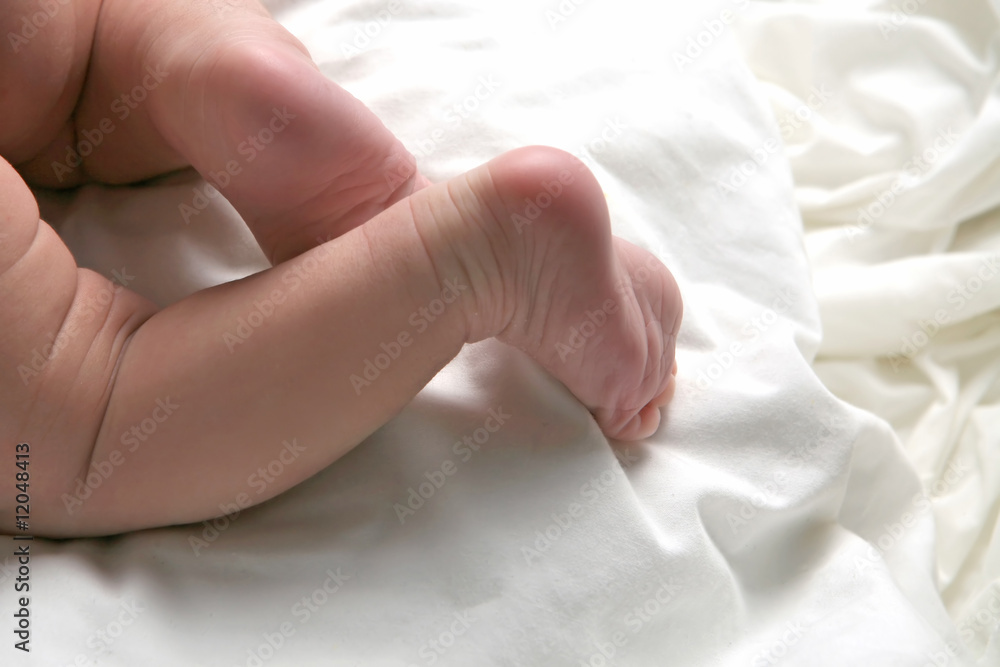 Cute Newborn Baby With Legs Lying Across White Blanket Cute Newborn Baby With Legs Lying Across White Blanket