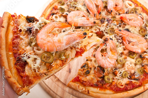 Whole seafood pizza with big shrimps, one slice cut out