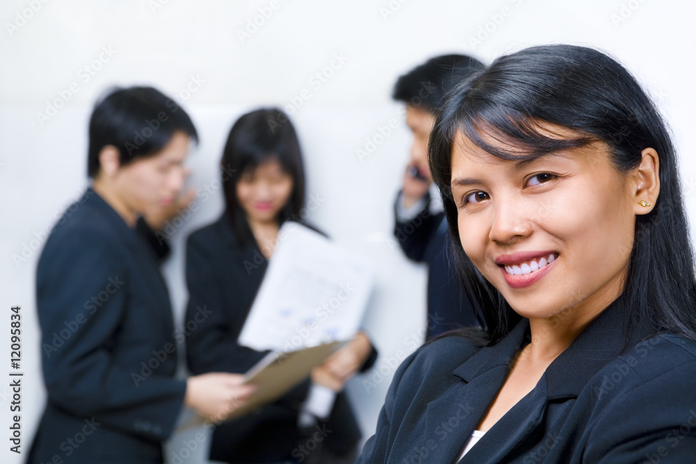 Young Asian Businesswoman smiling to camera with other people bu Young Asian Businesswoman smiling to camera with other people bu