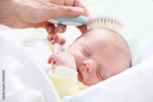 baby hygiene - mother brushing newborn's hair
