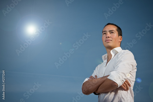 Asian man standing with arms folded