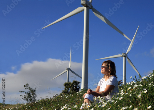 young woman dreams about the future on a wind farm beneath eolic