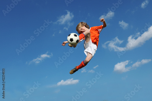 child playing football or soccer kicking ball