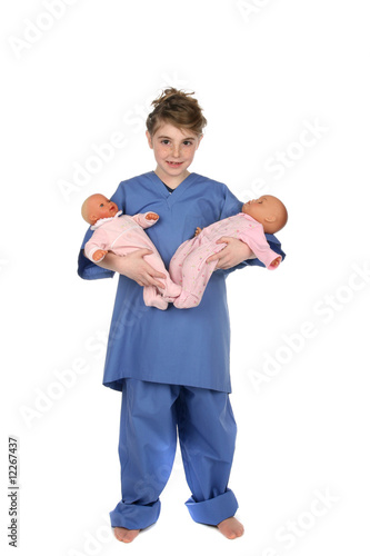 little girl in medical scrubs holding baby dolls