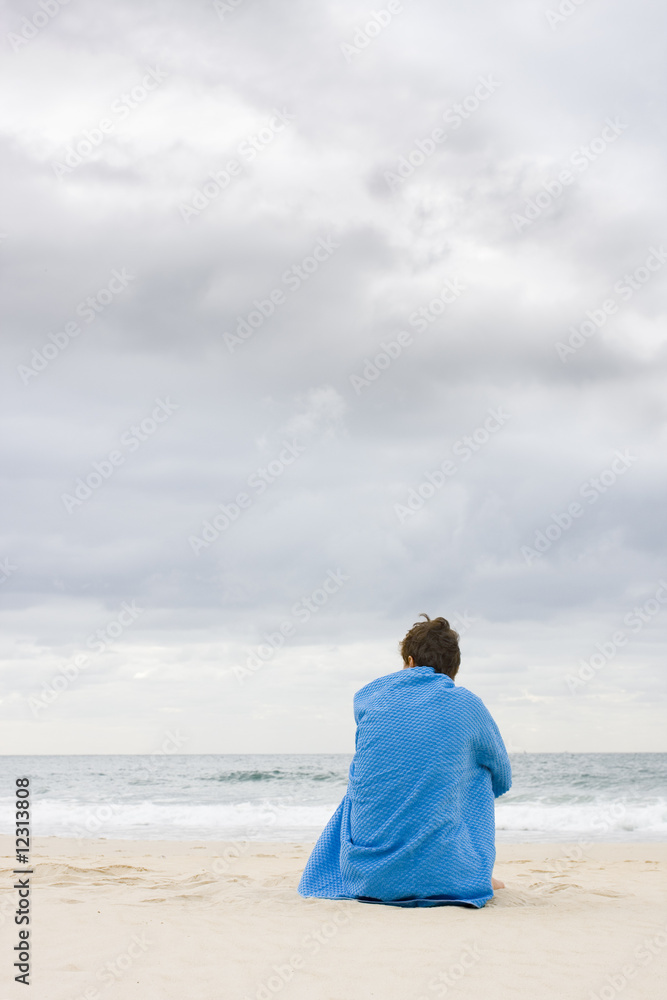 Frau sitzt allein am Strand