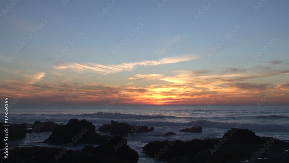 Ocean waves against rocks in the beach at sunset Ocean waves against rocks in the beach at sunset