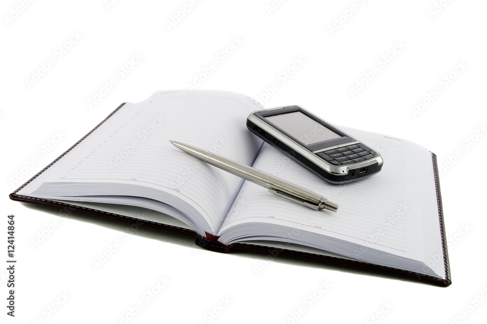 Close up noutbook, pen and mobile phone on it isolated over whit Close up noutbook, pen and mobile phone on it isolated over whit