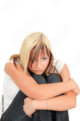 Young, depressed girl is sitting with sad face