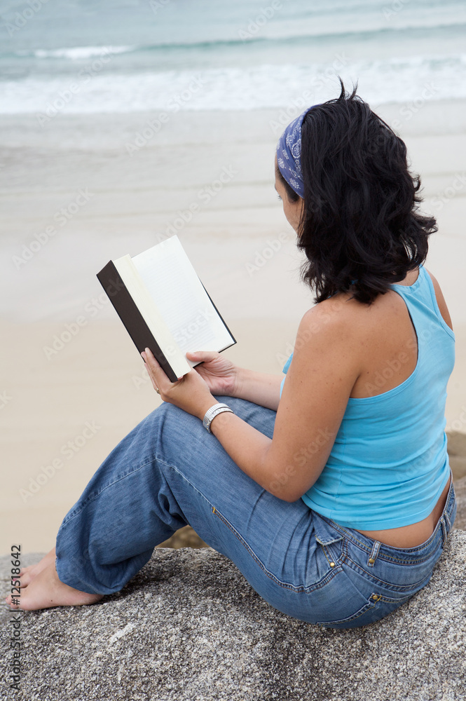 Young woman reading sitting on the beach