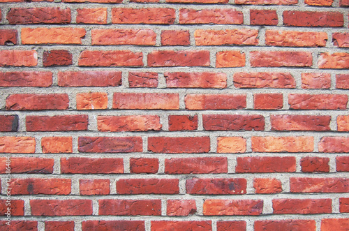 A close up of a red brickwall wtih grey plaster