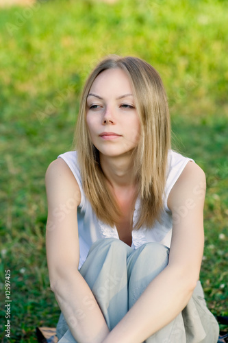 A beautiful young woman sitting on the grass
