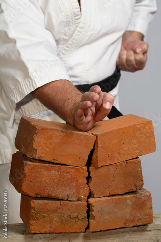 Fotografija karate man breaking three bricks on white background