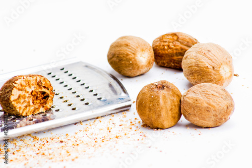 Several nutmegs with grater and fresh shavings