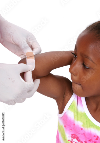 Hands placing bandage on girl's arm. photo