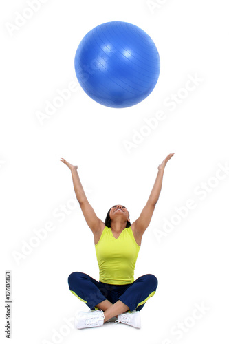 Beautiful 36 year old healthy woman tossing yoga ball into air.