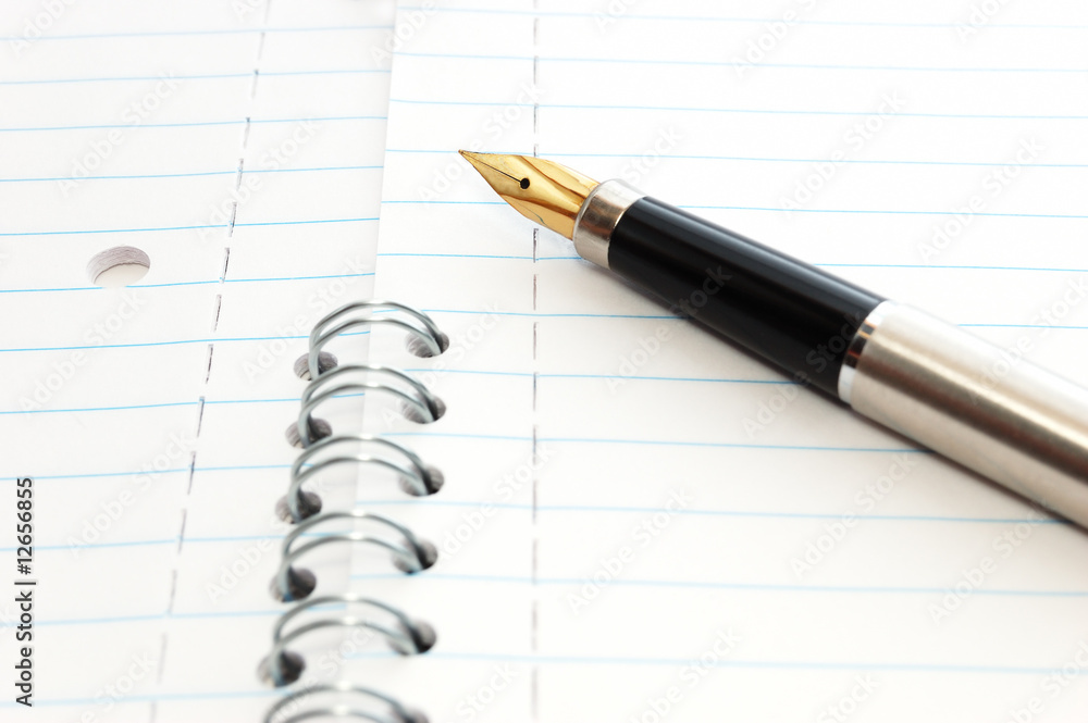 A gold-nibbed pen on a spiral-bound notepad A gold-nibbed pen on a spiral-bound notepad