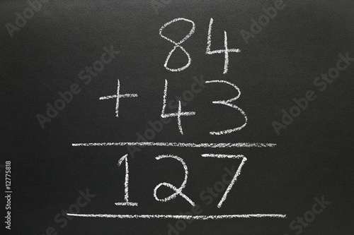A basic addition sum written on a blackboard.
