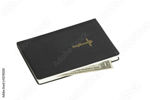 One dollar banknote inside black bible isolated on white
