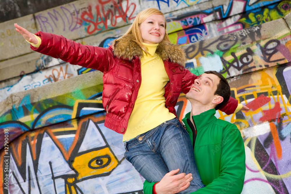 Happy smiling love couple fly backdrop of graphite wall Happy smiling love couple fly backdrop of graphite wall