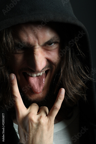 Young man with characteristic heavy metal tongue gesture