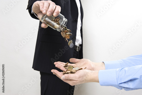 manager im anzug schüttet geldstücke in hand mit blauem hemd