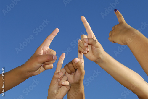 Several hands pointing high, with a blue sky