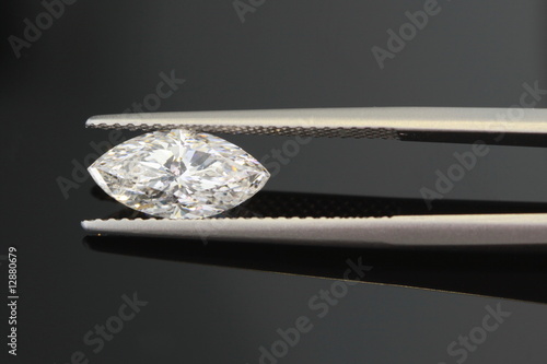 1.5 carat diamond being held with tweezers on black background