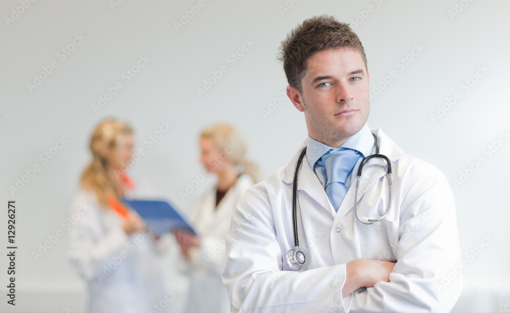 Doctor with two femal doctors in the background Doctor with two femal doctors in the background