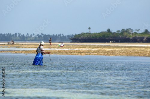 Black woman looking for a sea creature at the ebb, Zanzibar.