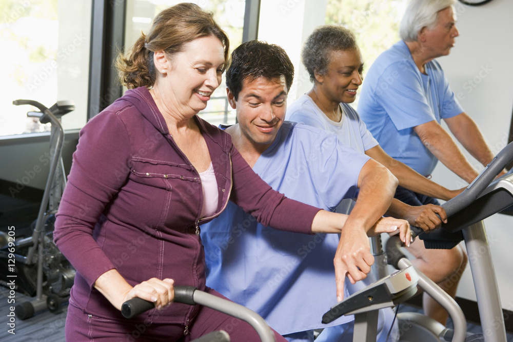 Nurse With Patient In Rehabilitation Using Exercise Machine