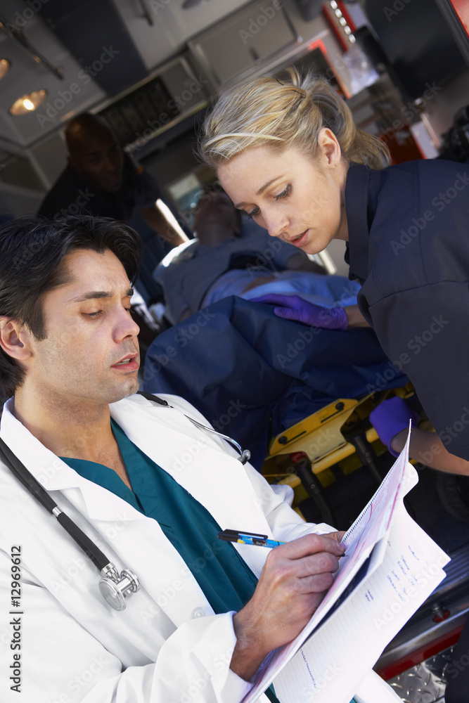 Paramedic advising doctor about arriving patient - obrazy, fototapety, plakaty 