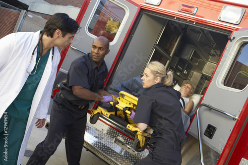 Paramedics and doctor unloading patient from ambulance photo