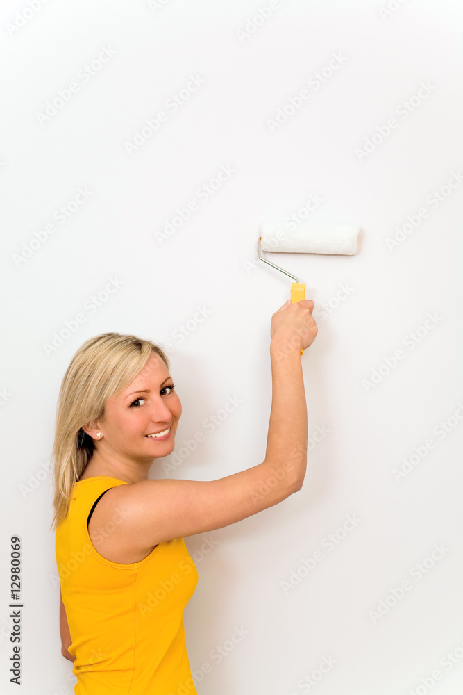 Woman painting wall with paint roller Woman painting wall with paint roller
