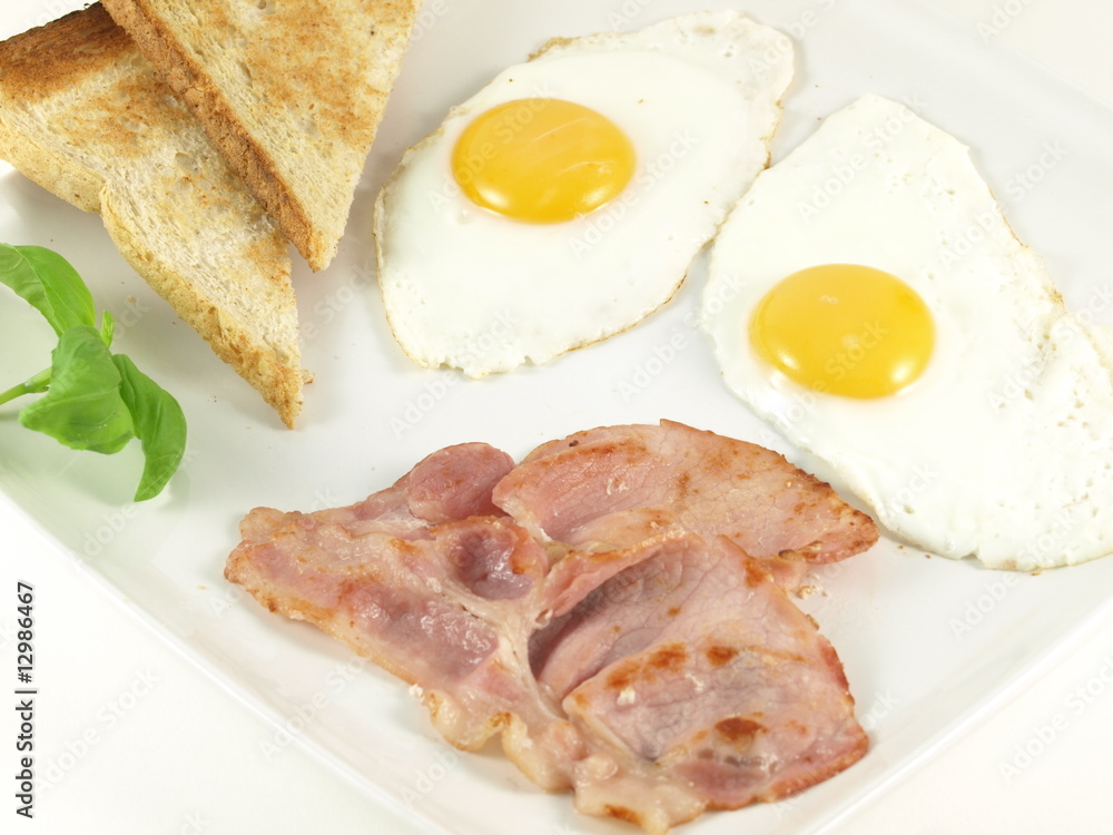 Fried eggs, bacon, toasts and basil on a plate. Fried eggs, bacon, toasts and basil on a plate.