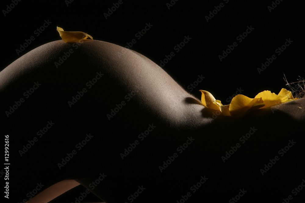 Fototapeta Piękne kształty kobiety obsypane żółtymi płatkami kwiatów.