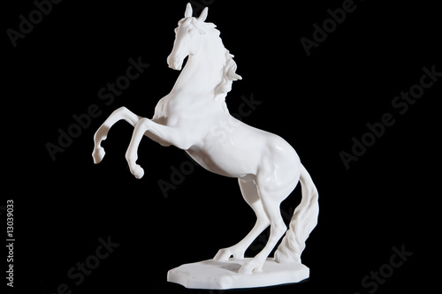 white marble statuette of bucking horse isolated on black