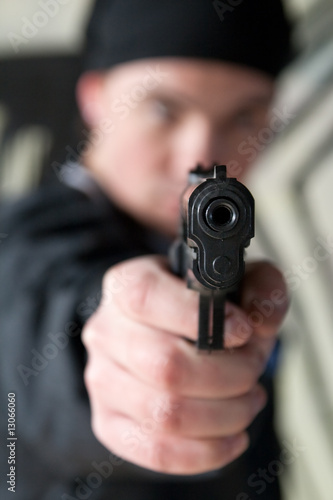 Young man pointing a gun straight at the camera