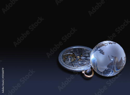 Glassy globe with old watch mechanism lying on dark © cosma