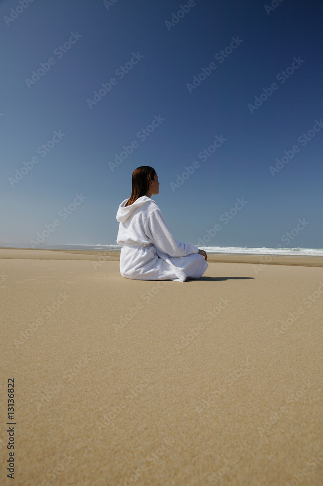jeune femme en peignoir assise à la plage