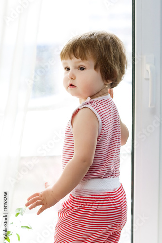 girl in striped dress standing at the window