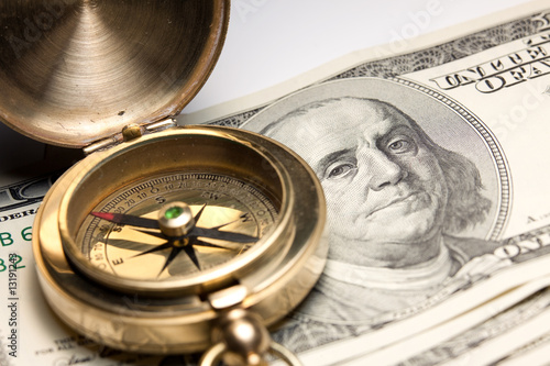 old vintage compass on a hundred usa dollar bill. focus on the e