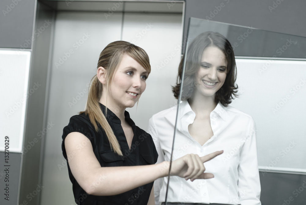 junge geschäftsfrauen zeigen auf glas display in büro junge geschäftsfrauen zeigen auf glas display in büro
