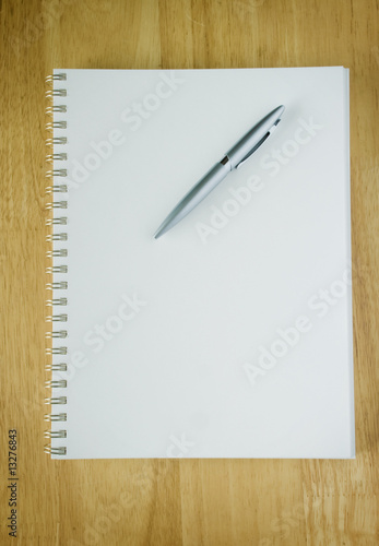 Blank spiral notebook with pen on wood table top