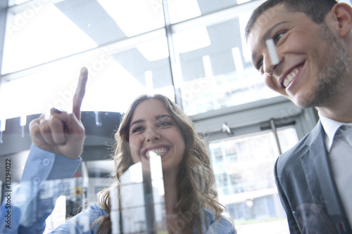 zwei kollegen zeigen auf scheibe bei meeting lachen