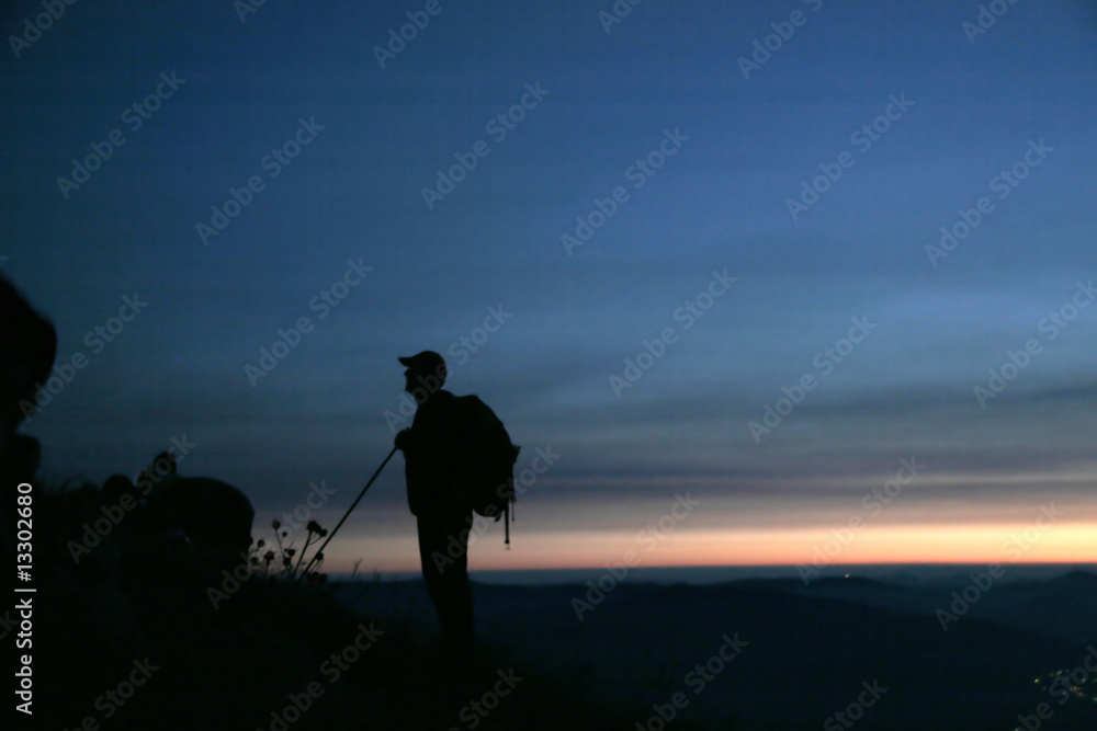 Mountaineer waiting for sunrise at the top of the mountain
